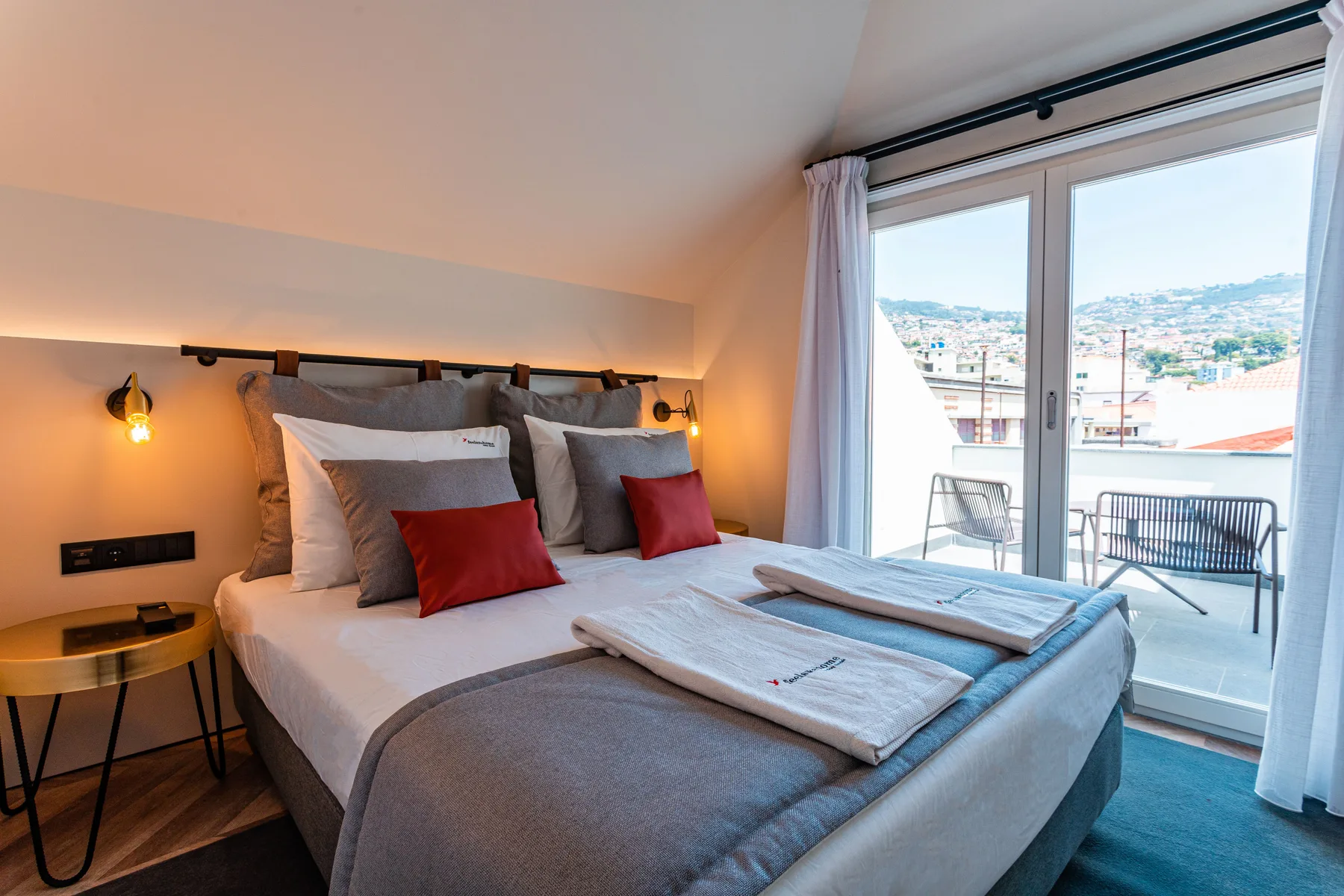 A bedroom with a large bed beside sliding glass doors opening onto a balcony.
