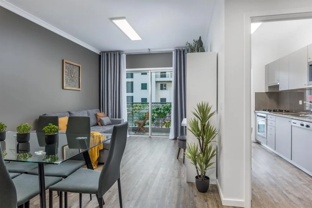 A living and dining area with seating beside a glass balcony door.