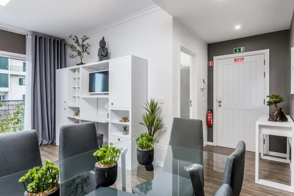 A bright living and dining area with a glass table and white shelving.