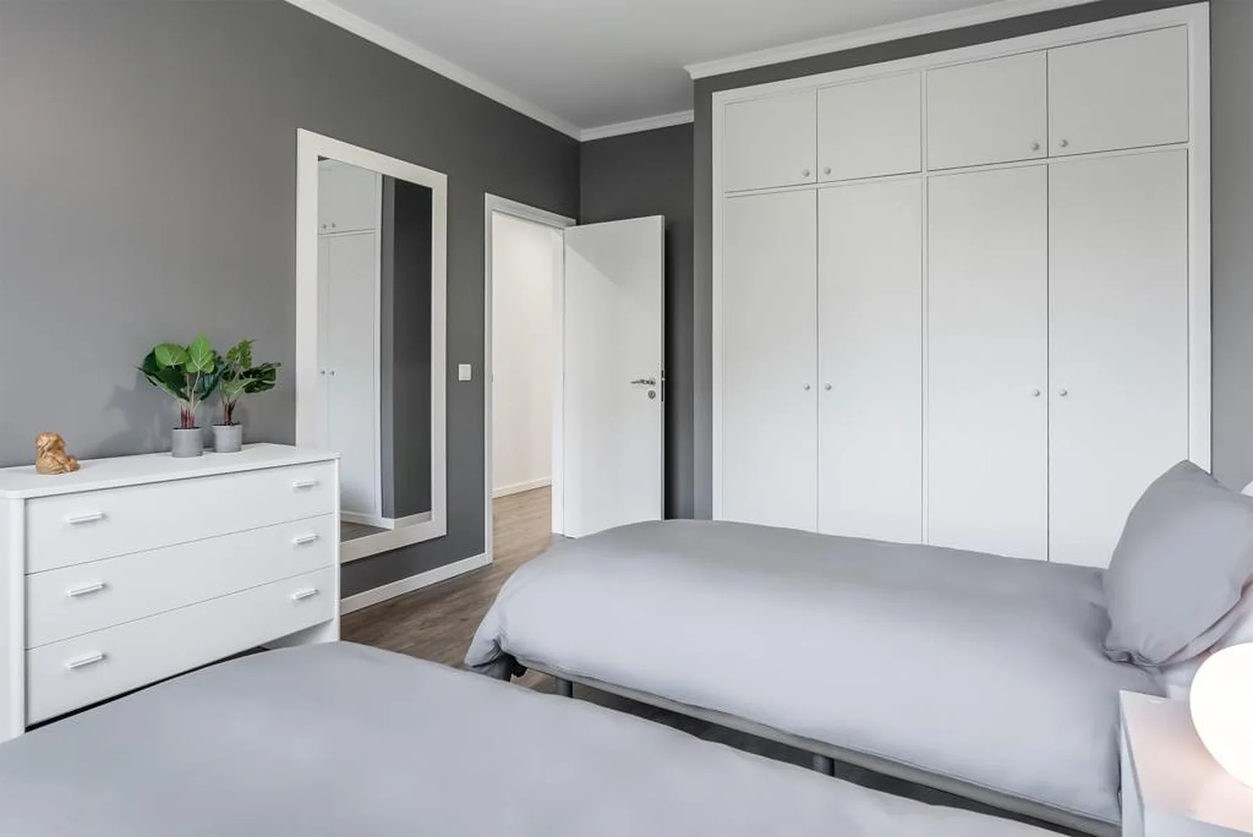 A bedroom with two beds, a white wardrobe, and a dresser.