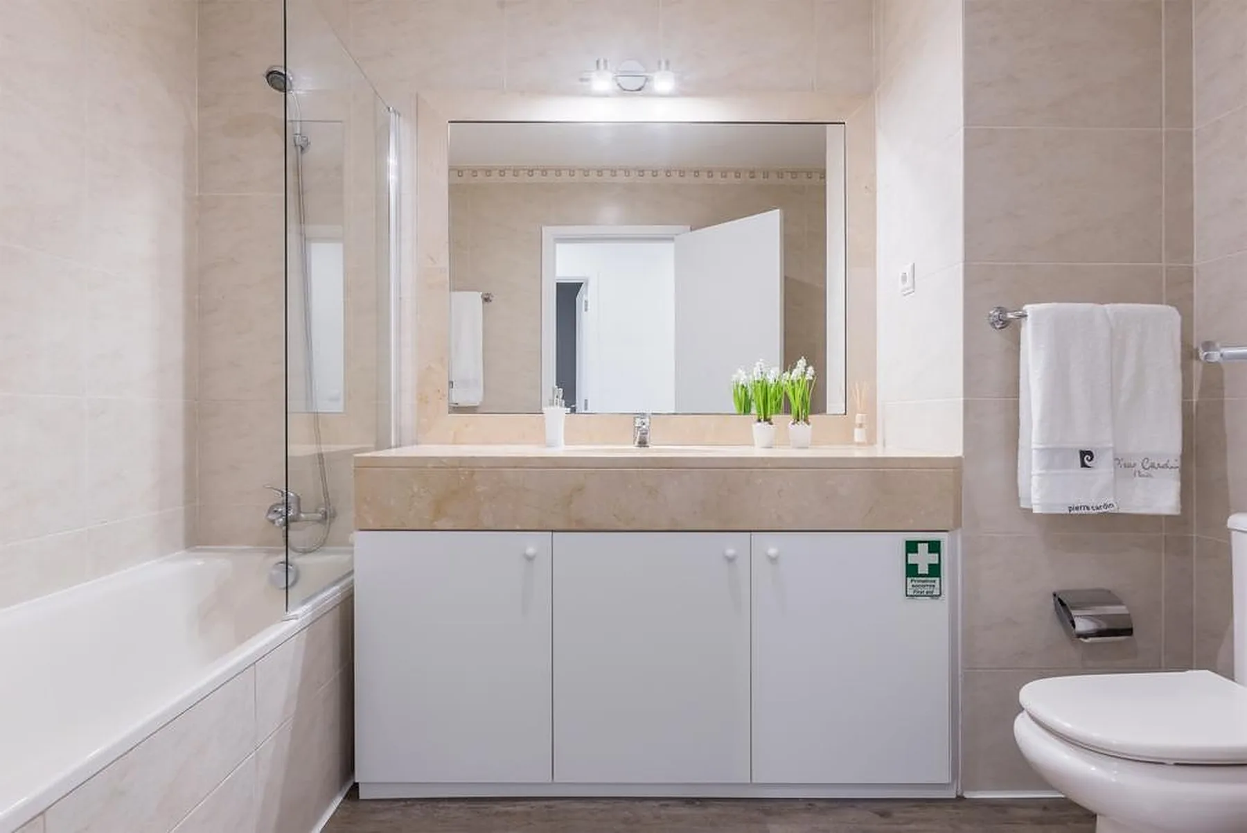 A bathroom with a bathtub, vanity, and wall mirror.