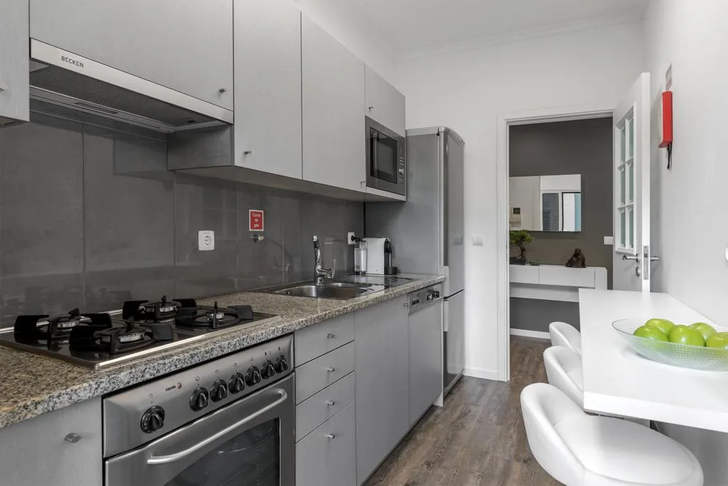 A modern kitchen with gray cabinets, a countertop, and a dining table.