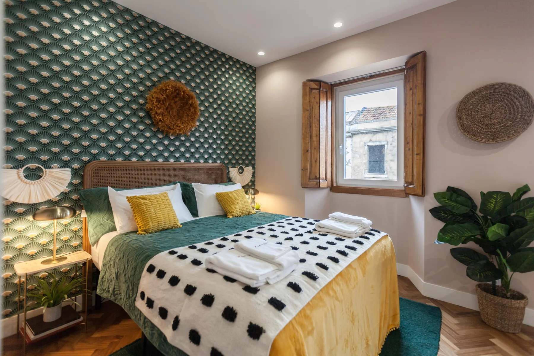 A bedroom with green patterned wallpaper, a bed, and a window.
