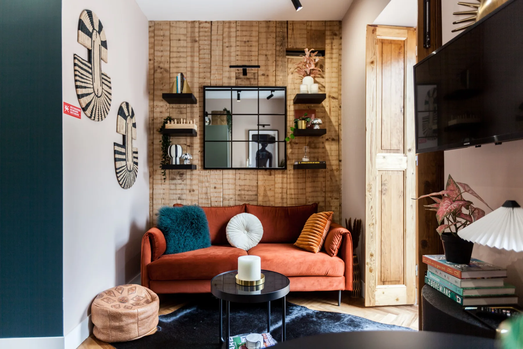 A colorful living room with a rust-colored sofa, patterned wall, and coffee table.