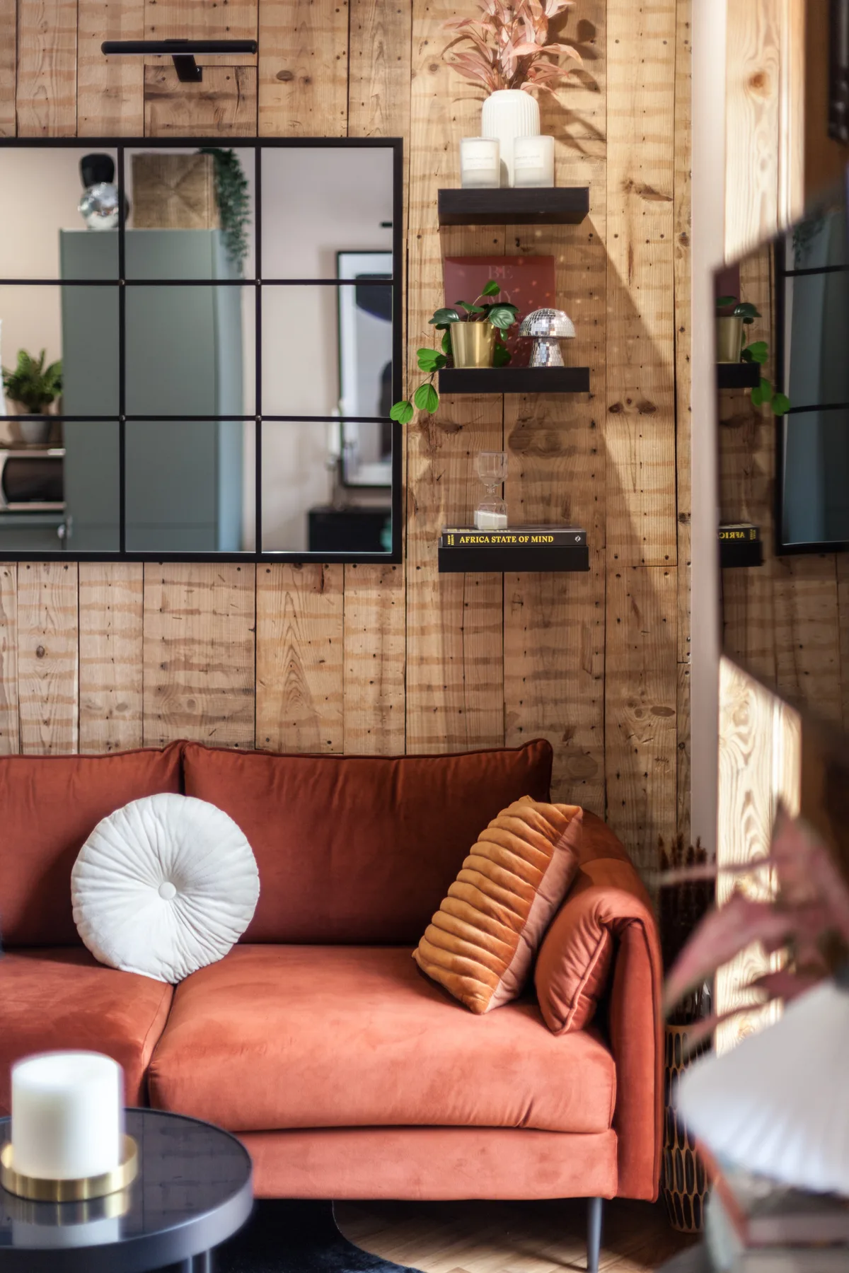 A living room with rust-colored seating and wood-paneled walls.