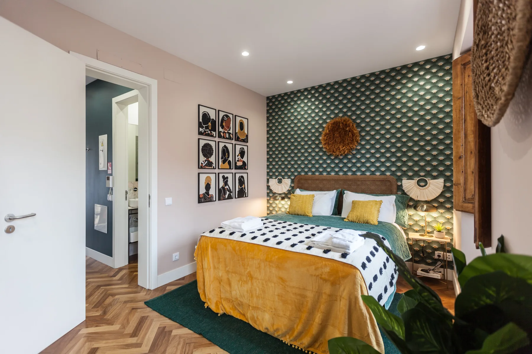 A bedroom with a bed against a patterned accent wall and framed artwork.
