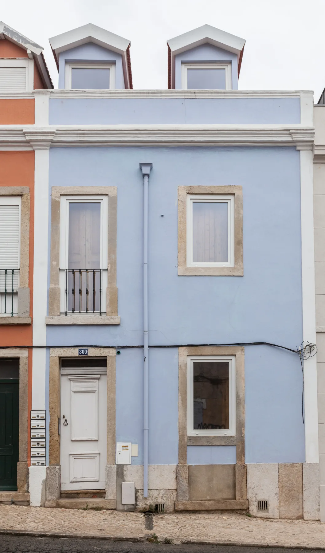 A light blue building facade with windows, a front door, and roof dormers.