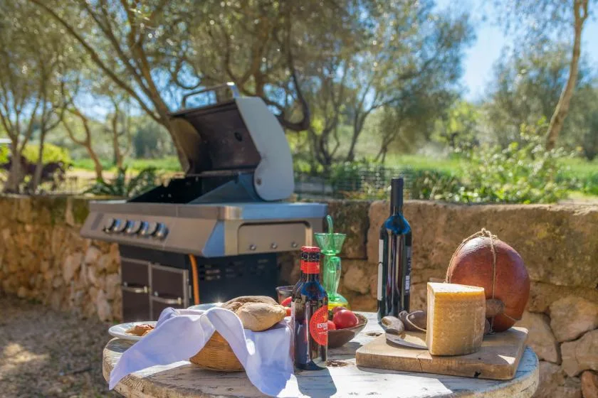 An outdoor barbecue area with a grill and a table set with food.