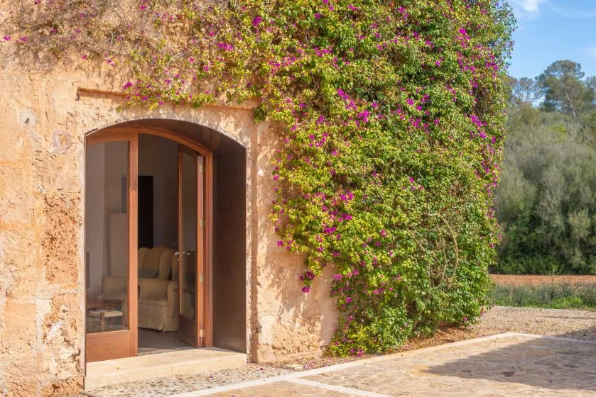 An arched doorway opens onto a stone terrace beside flowering vines.