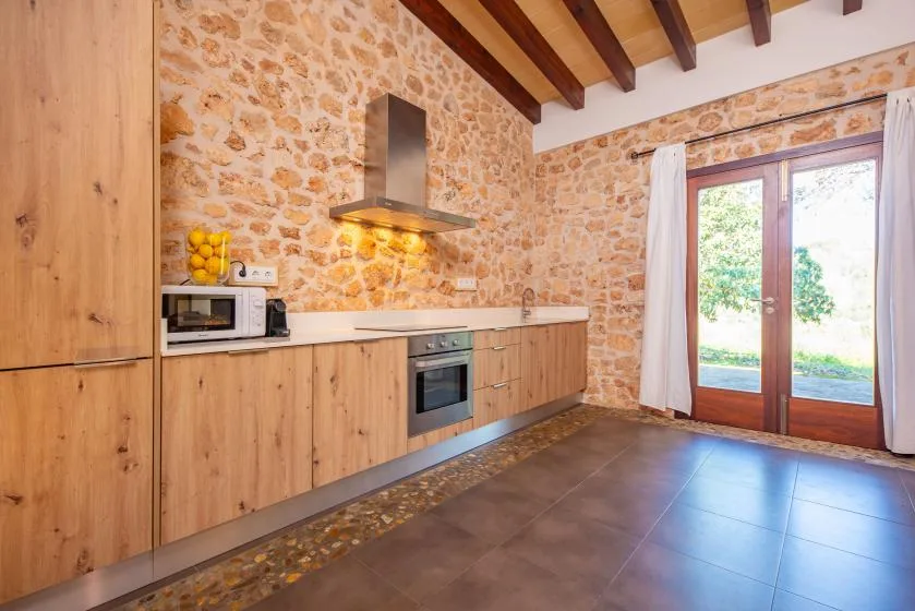 A rustic kitchen with wood cabinets and glass doors opening to a garden.