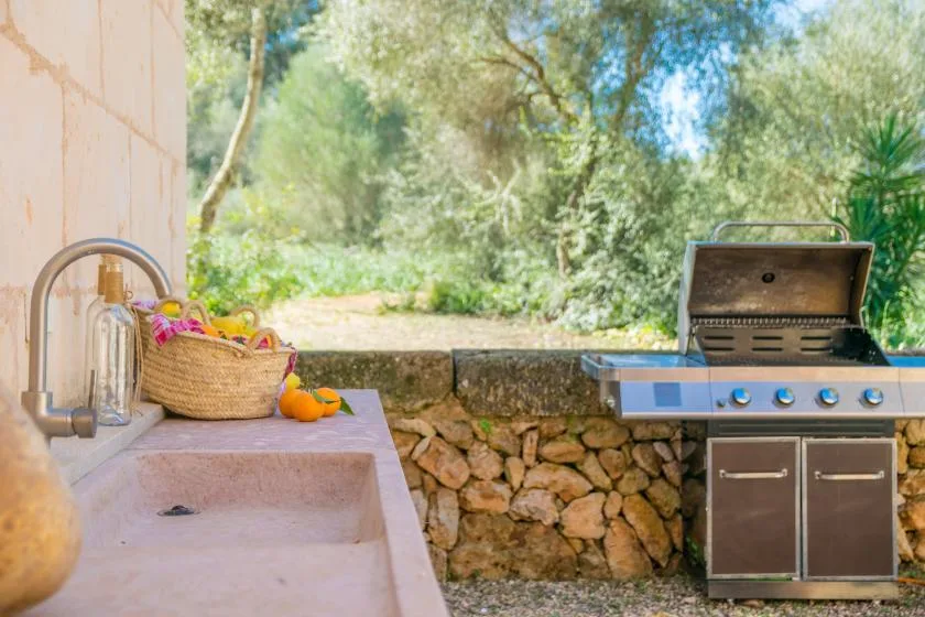 An outdoor cooking area with a built-in sink and an open barbecue grill.