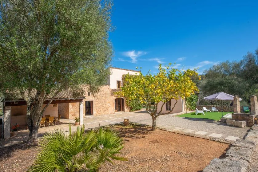 A courtyard with a stone house, trees, and an outdoor seating area.