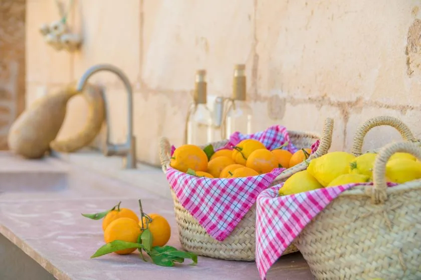 A kitchen counter displays baskets of citrus fruit beside a sink.