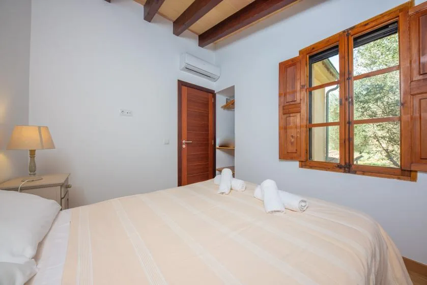 A bedroom with a bed beneath a wooden-framed window.