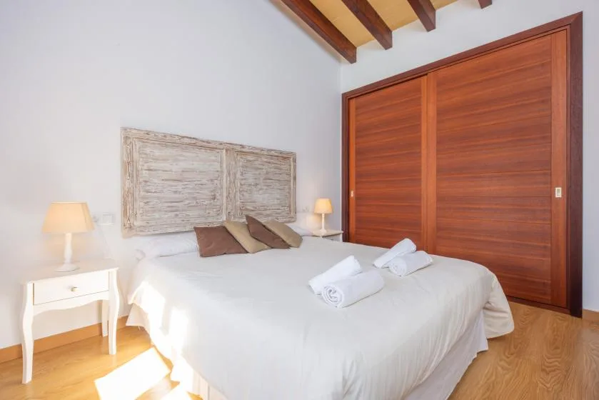 A bedroom with a white bed, bedside tables, and wooden sliding doors.