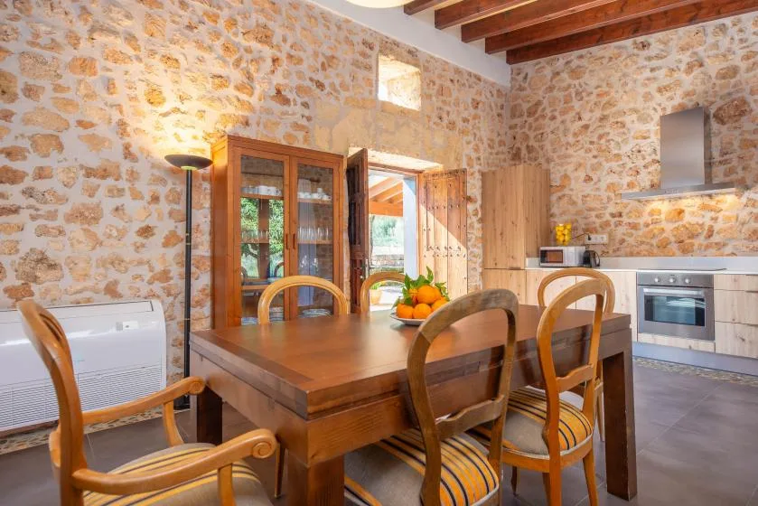 A rustic kitchen and dining area with a wooden table beneath exposed ceiling beams.