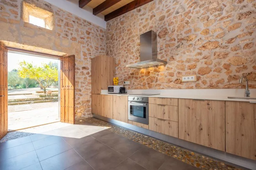 A rustic kitchen with wooden cabinets, a stove, and an open doorway.