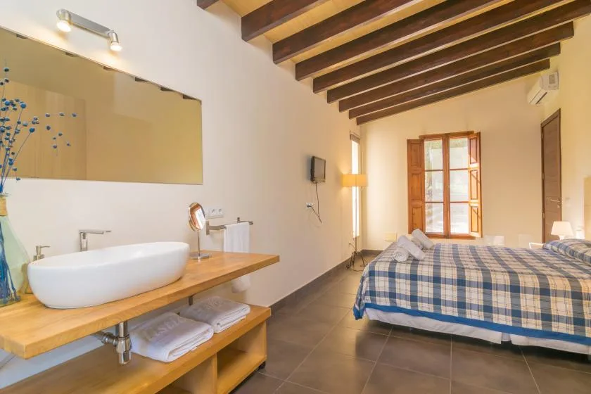 A bedroom with a bed beside a washbasin counter and a window.