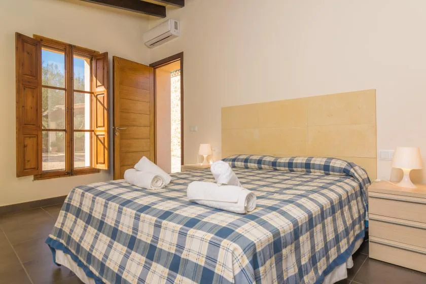A bedroom with a large bed covered in blue-and-beige plaid bedding.