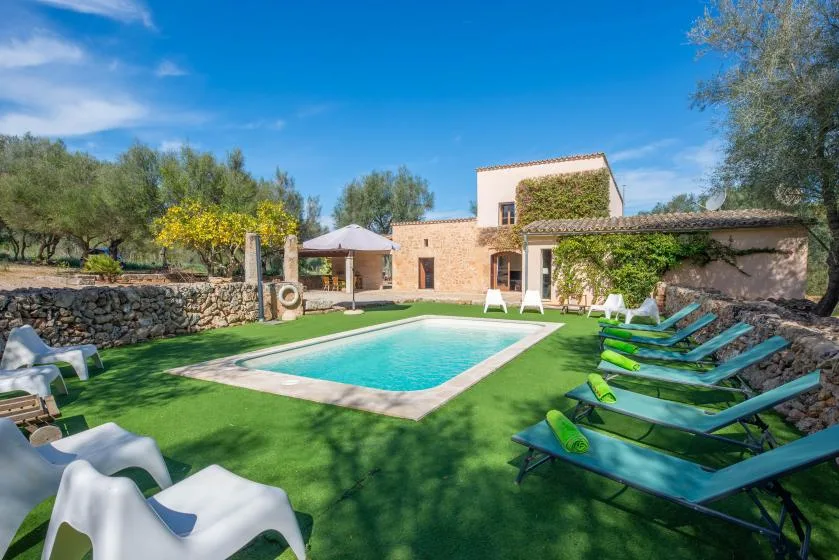 Una piscina al aire libre está en un patio con césped junto a un edificio de piedra.