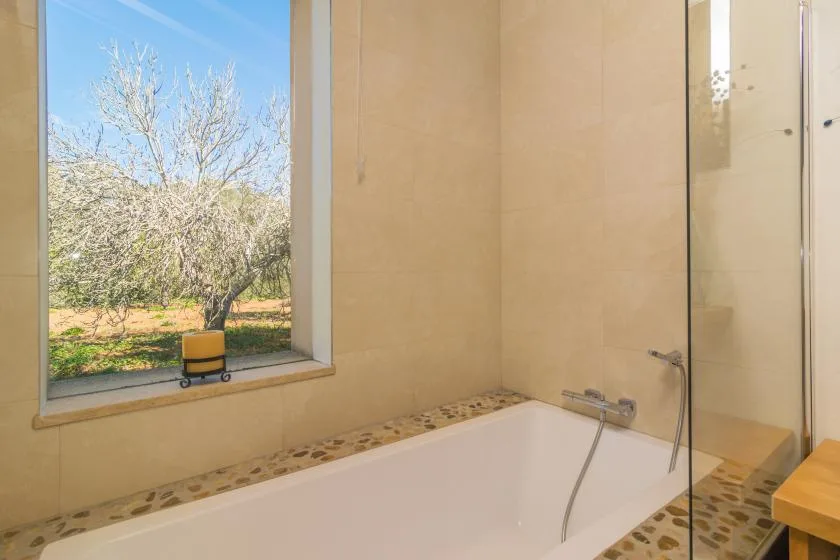A bathroom with a bathtub beside a large window.