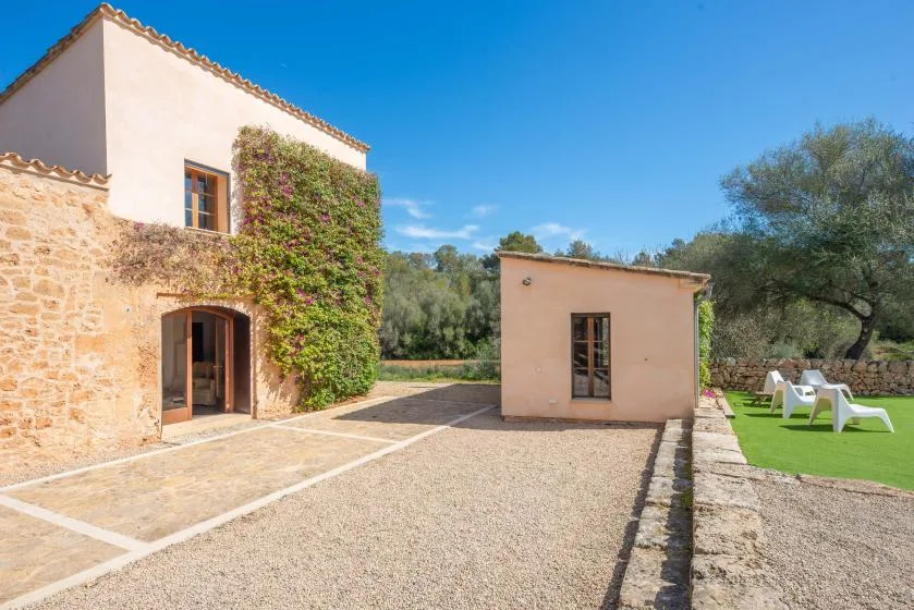 A courtyard between a stone building and a smaller outbuilding, with outdoor seating nearby.