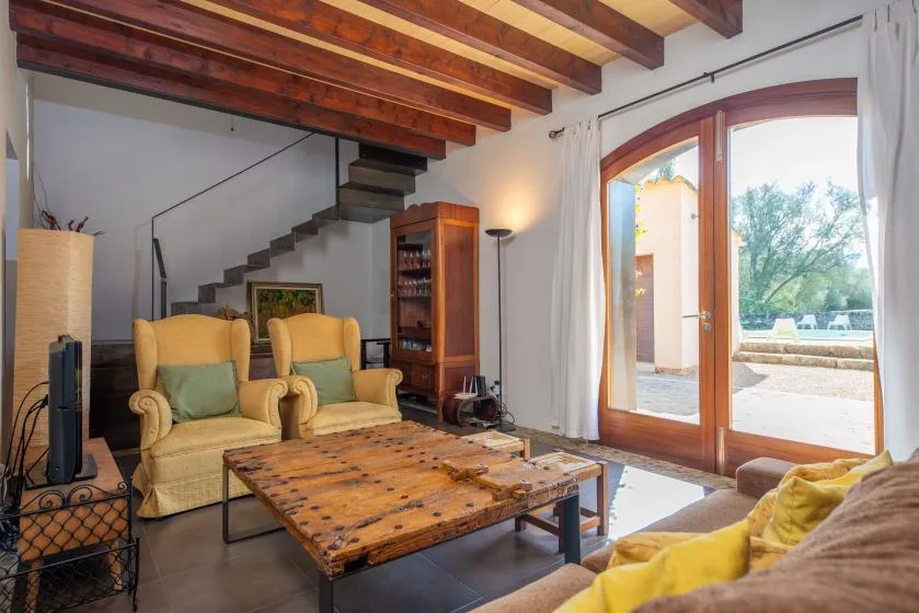 A living room with seating and a wooden coffee table beneath exposed ceiling beams.