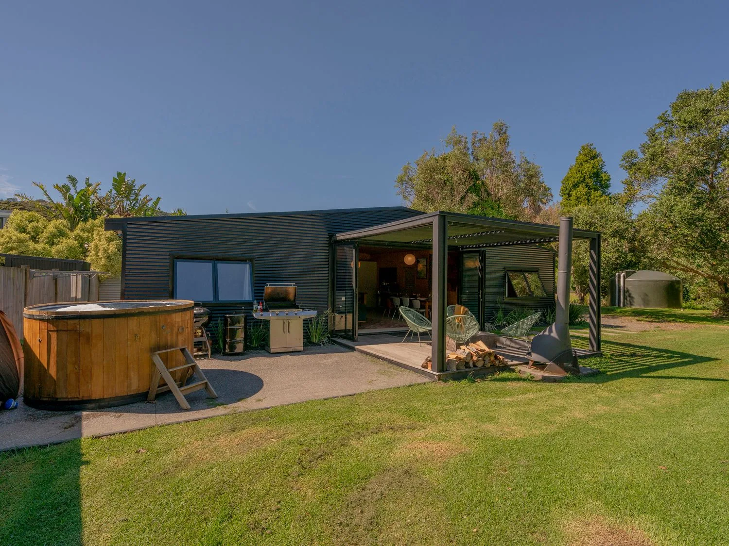 Un patio moderno con jacuzzi exterior y una zona de estar cubierta.