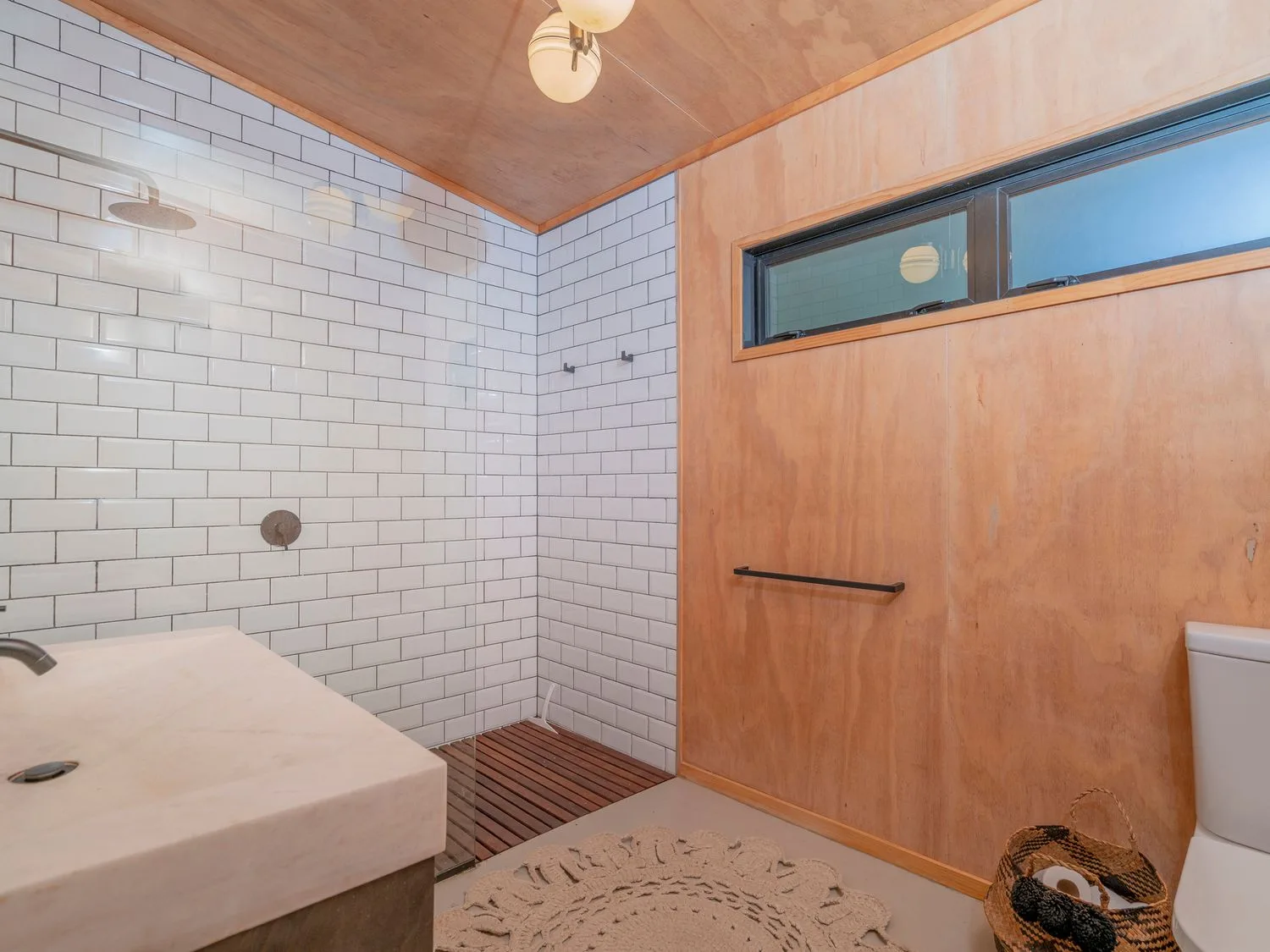 Un baño con paredes de azulejos blancos, techo de madera y un lavabo.