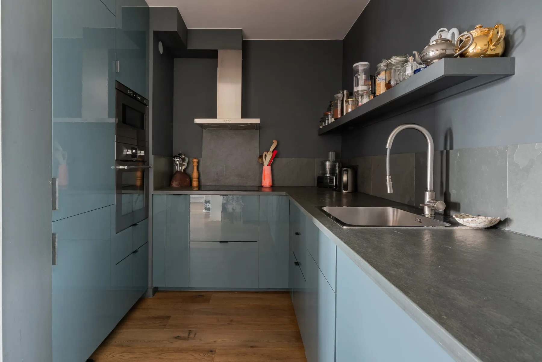 A modern kitchen with blue cabinets, a dark countertop, and a sink.
