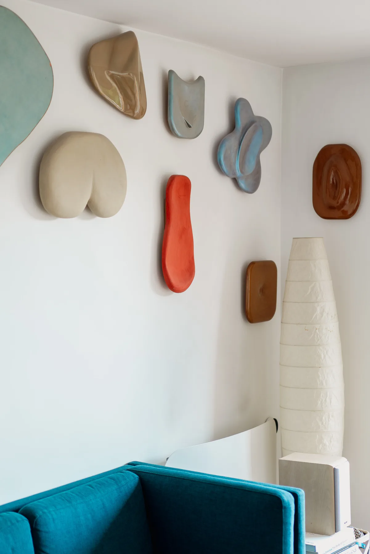 A living room corner with a teal sofa and sculptural wall decorations.