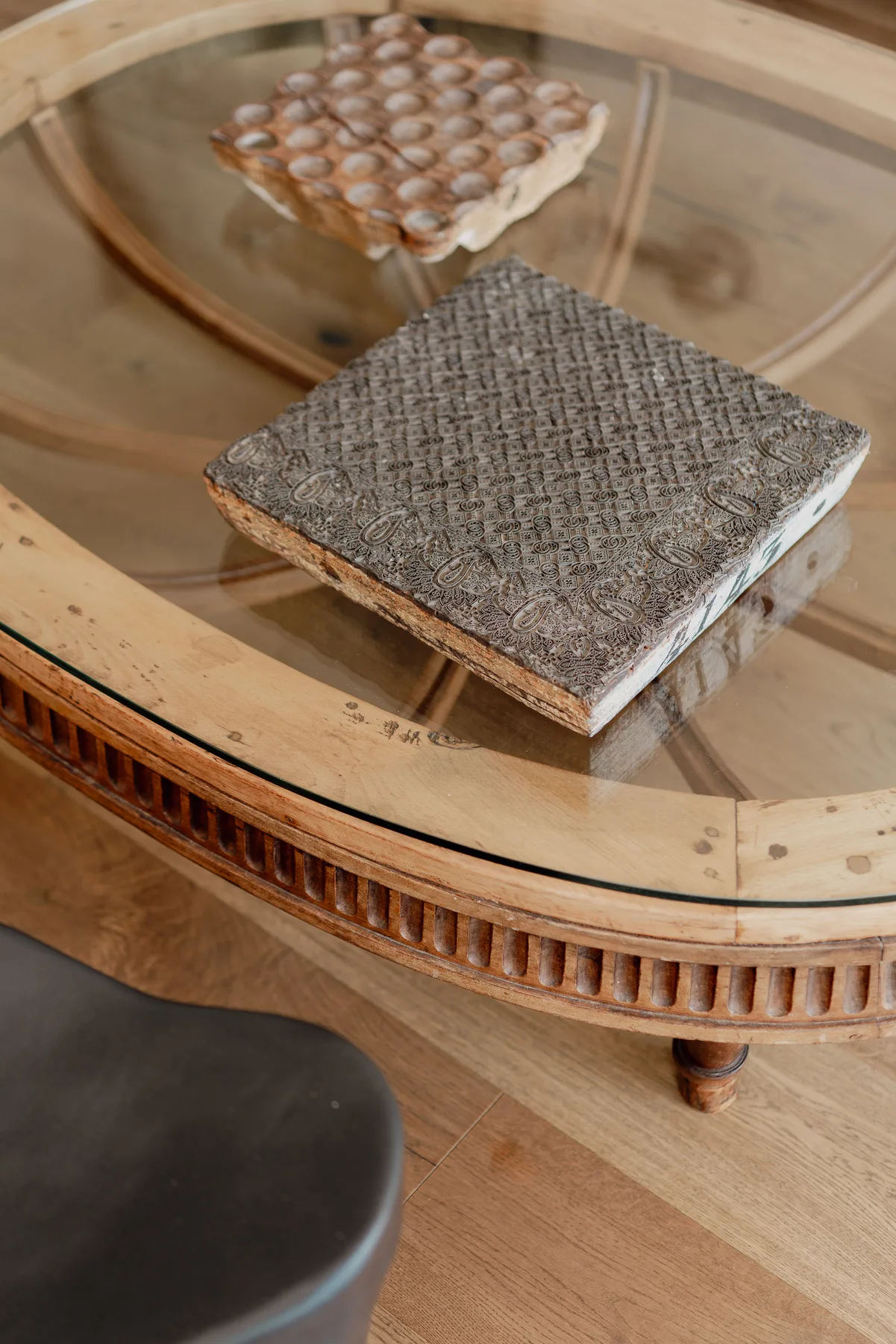 A glass coffee table holds two textured square pieces in a living area.