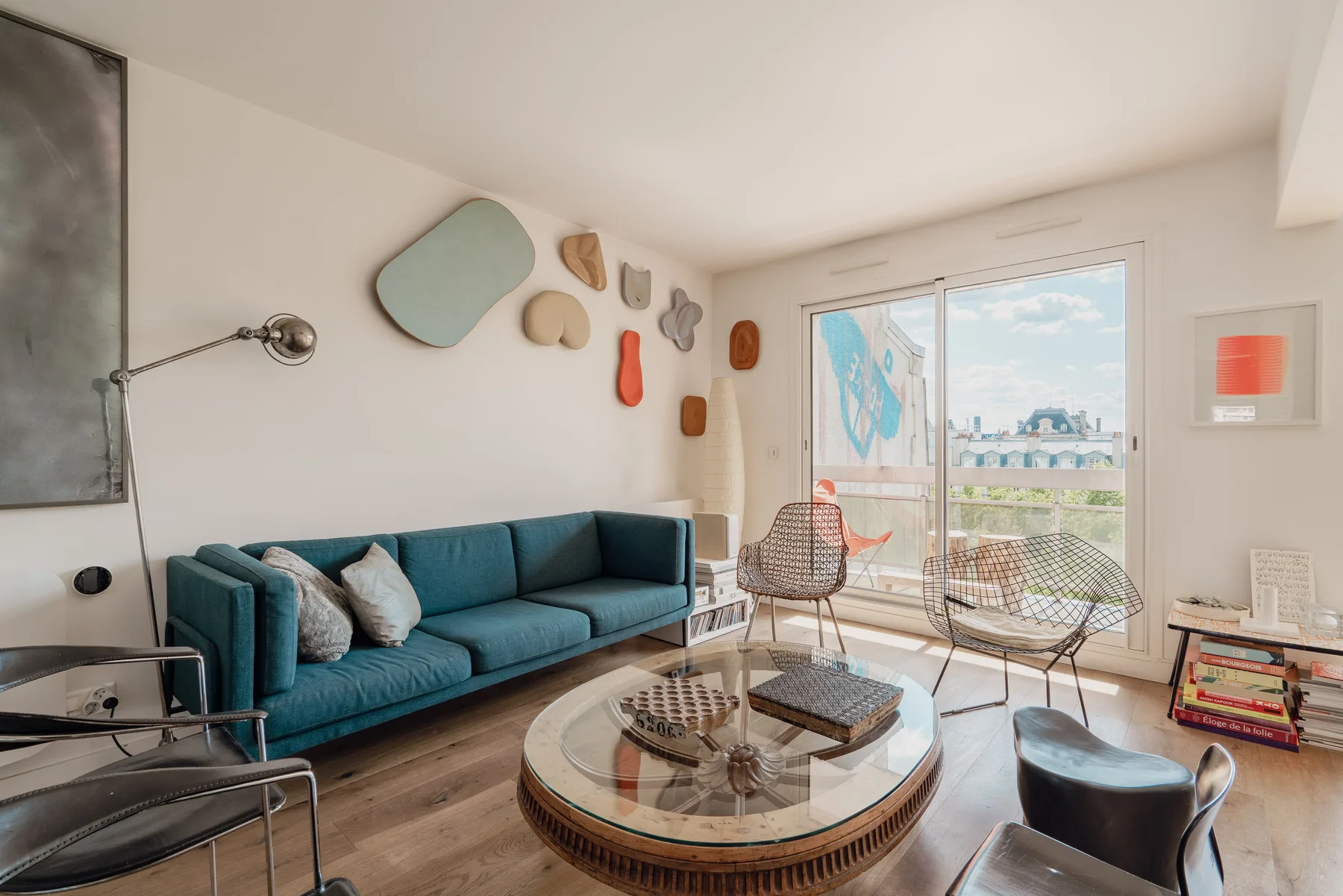 A bright living room with teal seating, a round coffee table, and sliding glass doors.