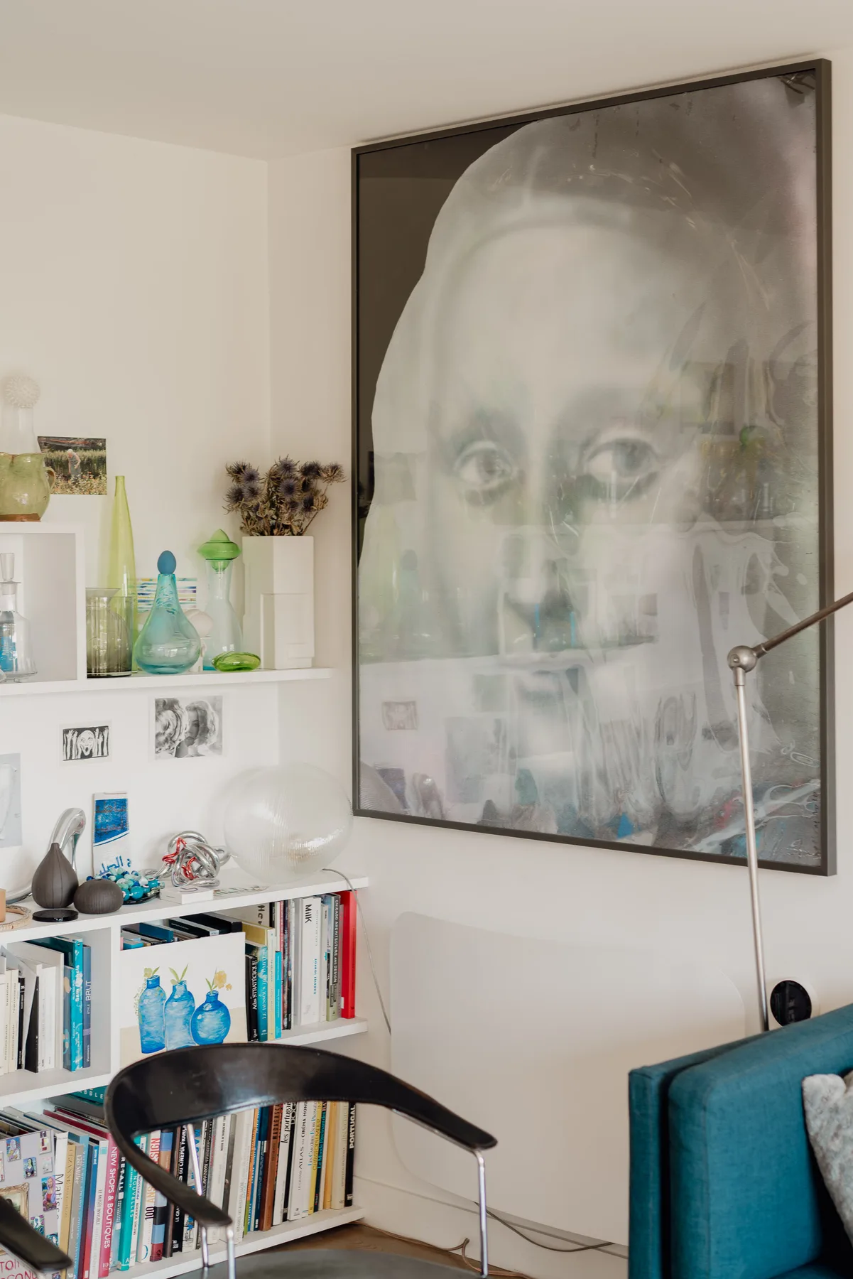 A living room with a large framed portrait above a bookcase and seating.