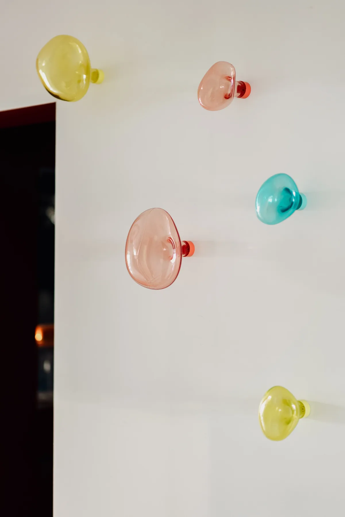 A white wall displays several colorful, rounded wall lights.