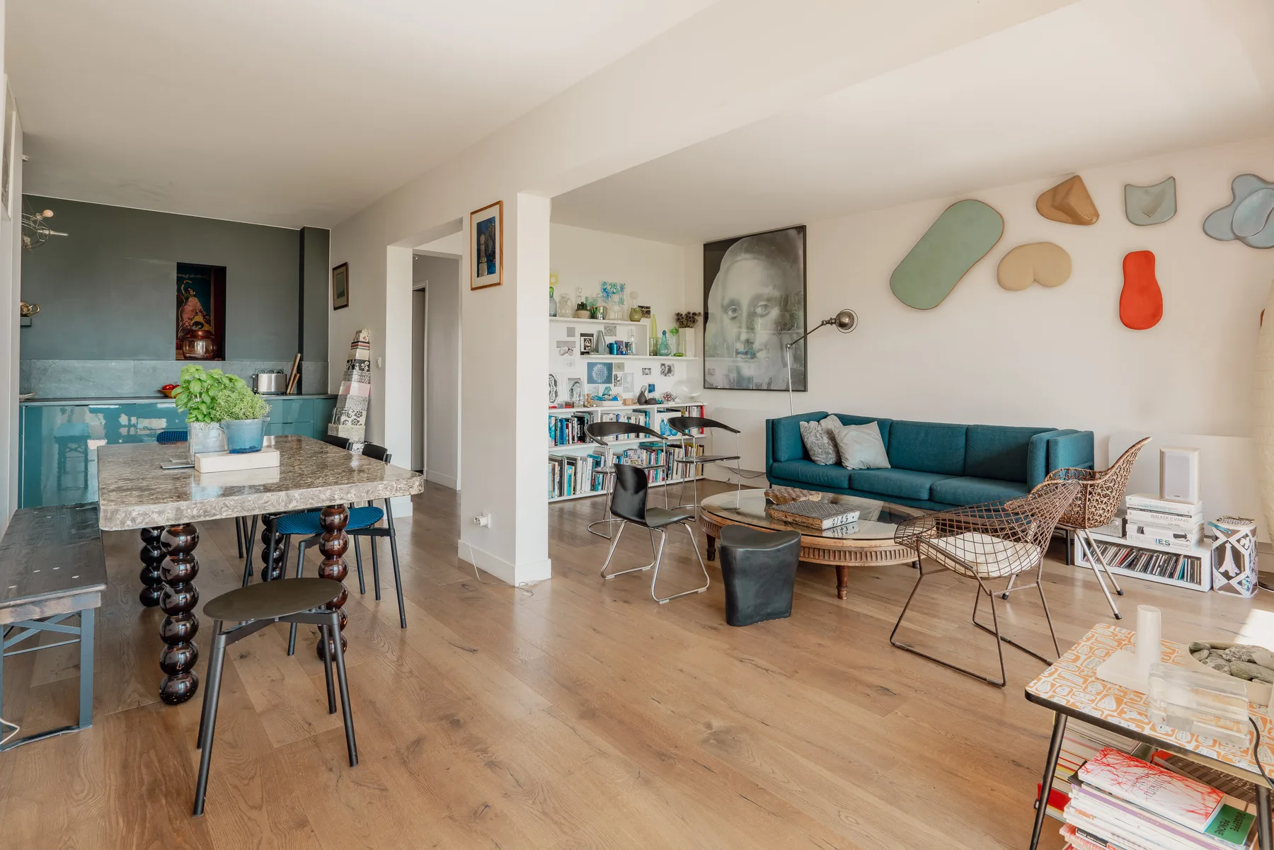 An open-plan living and dining area with teal seating and a table.