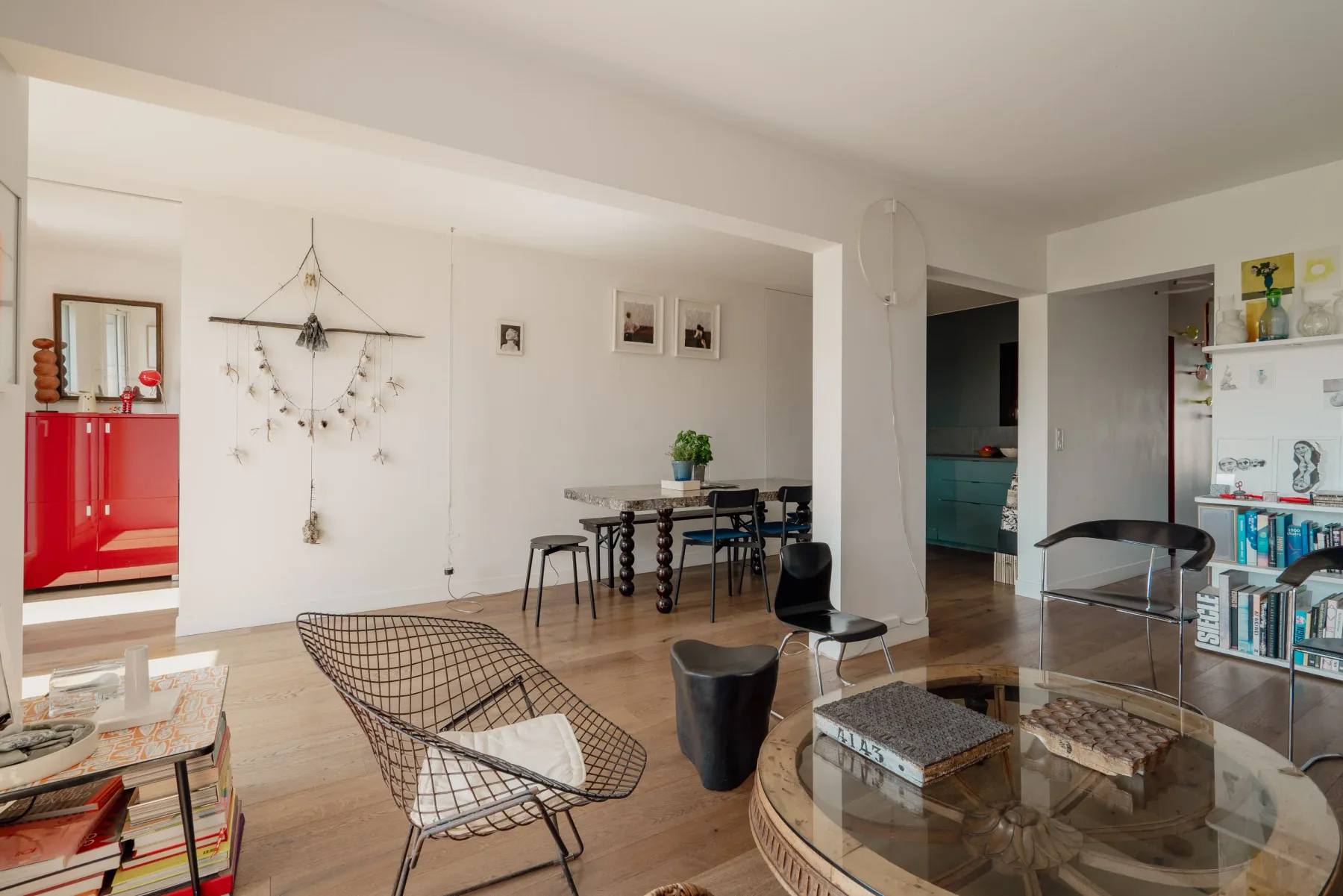 A bright dining and living area with a table, wire seating, and a glass coffee table.