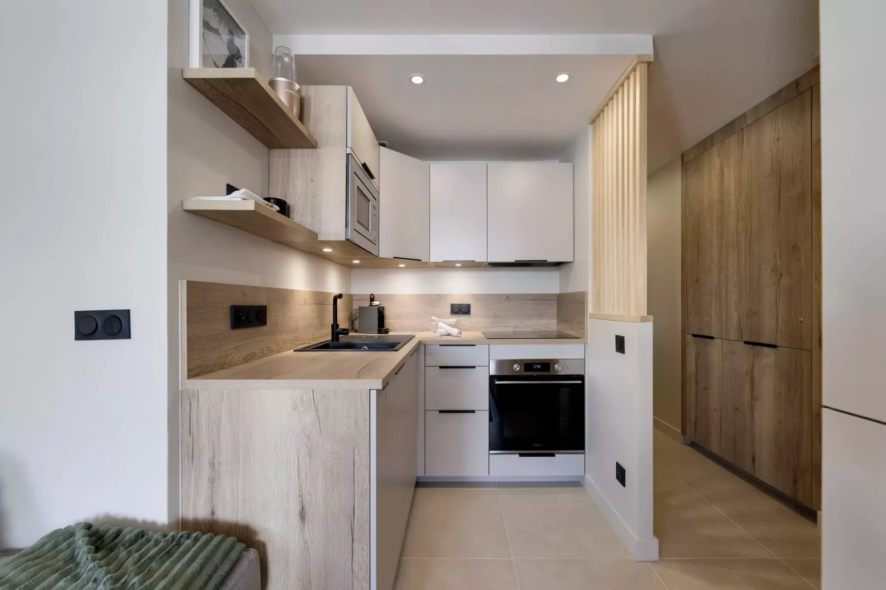 Una cocina moderna con gabinetes claros, una encimera y un horno integrado.