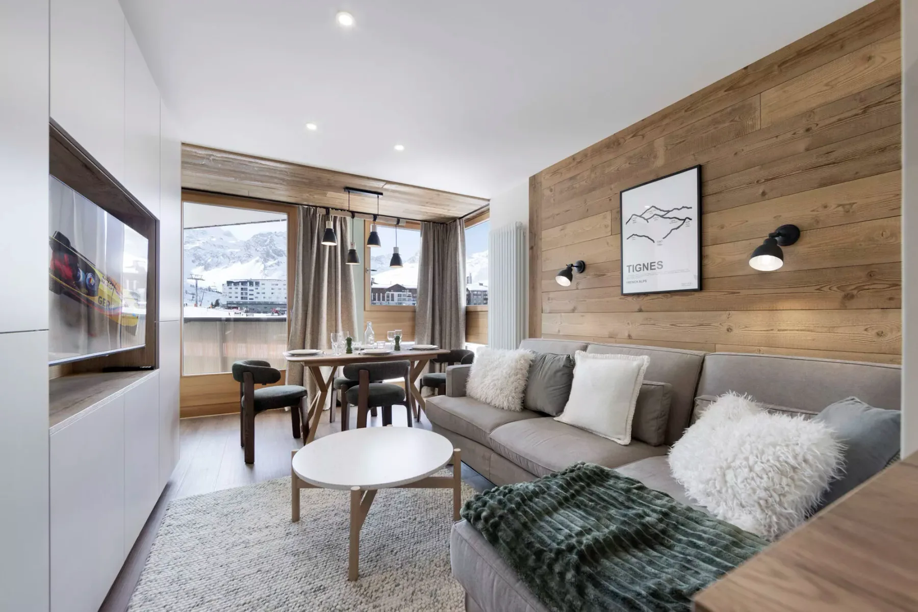 A modern living and dining area with a sectional sofa and a table by the windows.