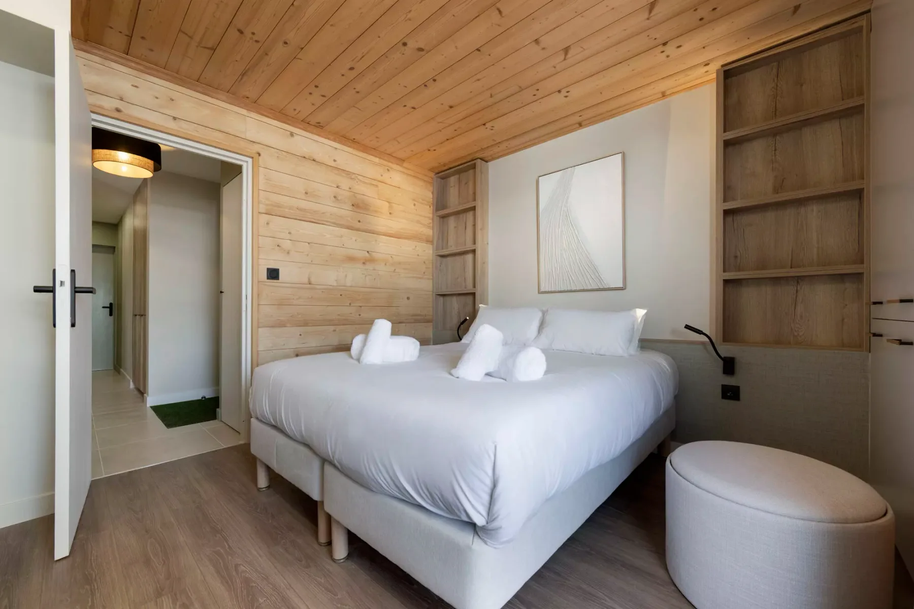 Un dormitorio con una cama grande, estanterías empotradas y paredes de madera clara.