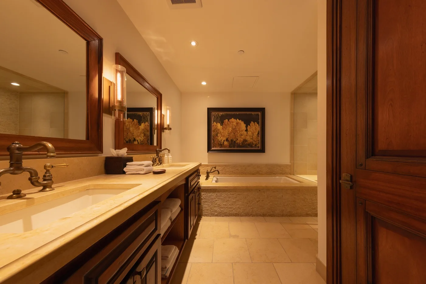 A spacious bathroom has a long vanity beside a built-in bathtub.
