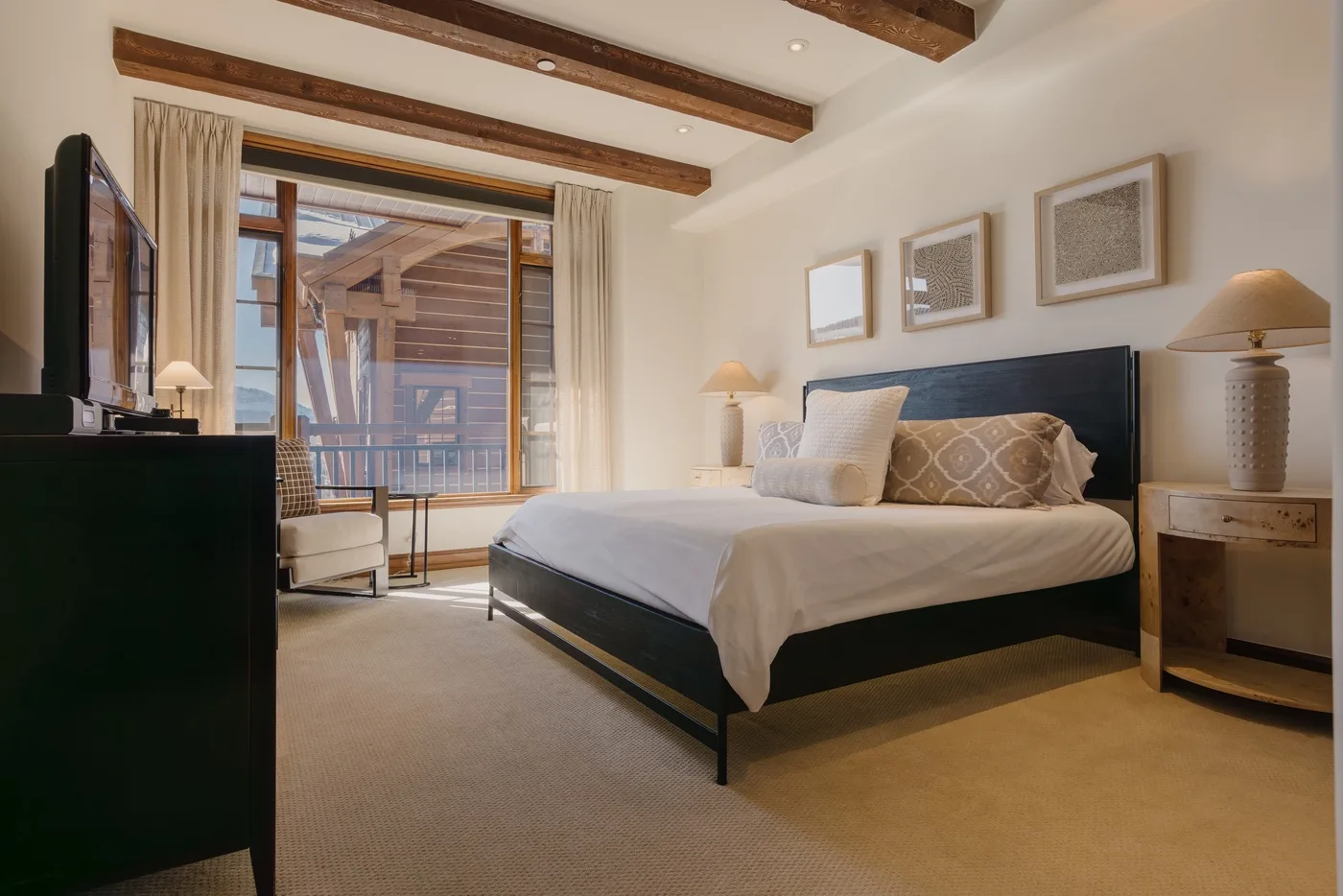 A bedroom with a large bed, bedside tables, and a glass door to a balcony.