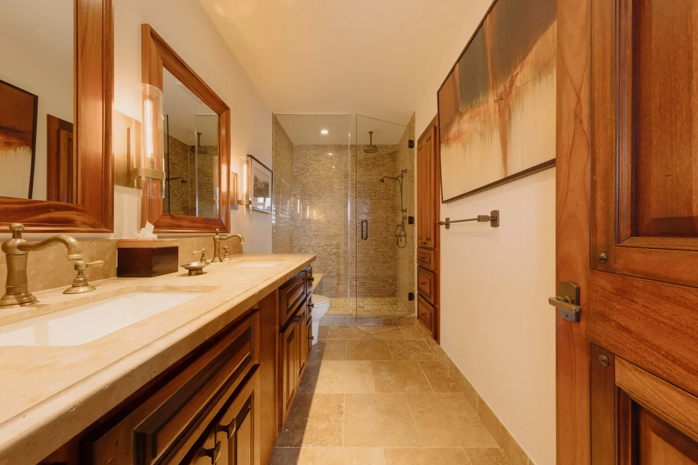 A bathroom with a long vanity and a glass-enclosed shower at the far end.