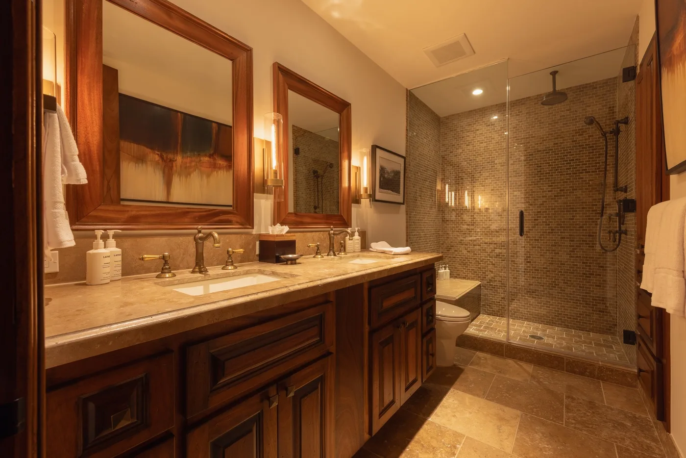 A bathroom with a long vanity and a glass-enclosed shower.
