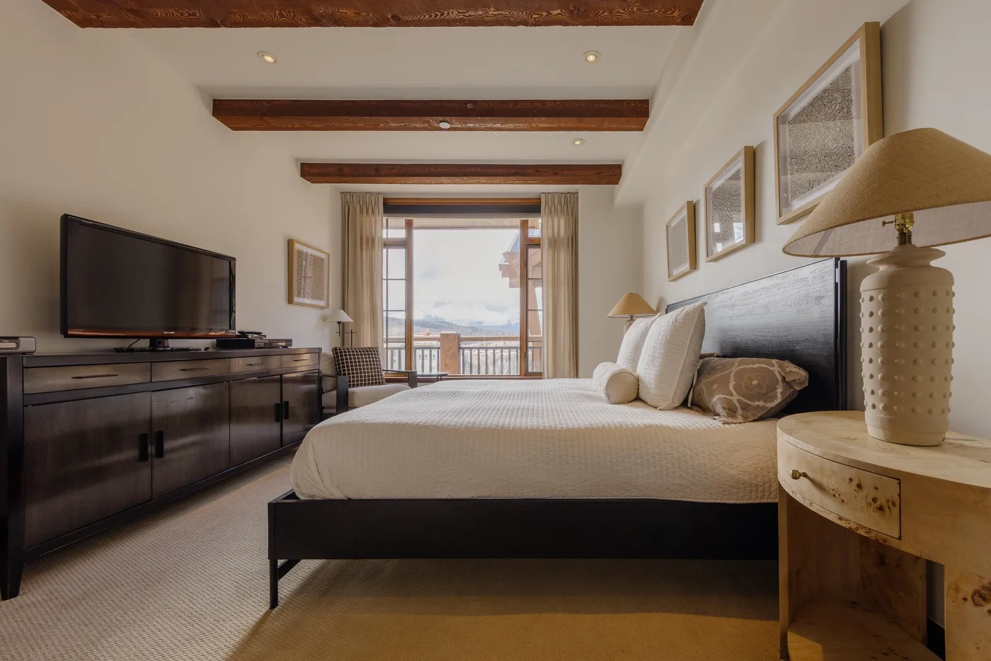 A bedroom with a neatly made bed and a balcony visible through the glass doors.