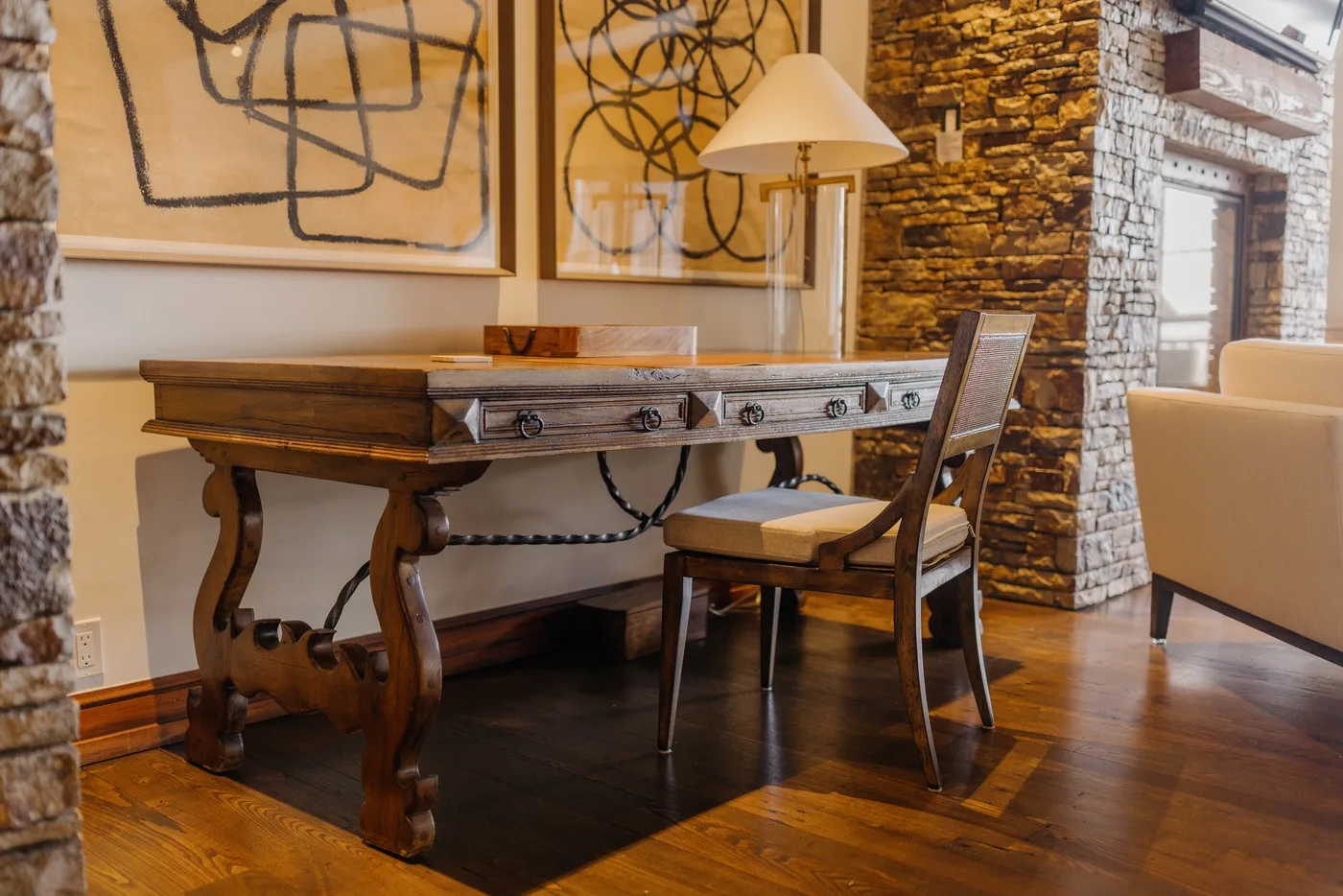 A dining area with a wooden table, seating, and abstract artwork on the wall.