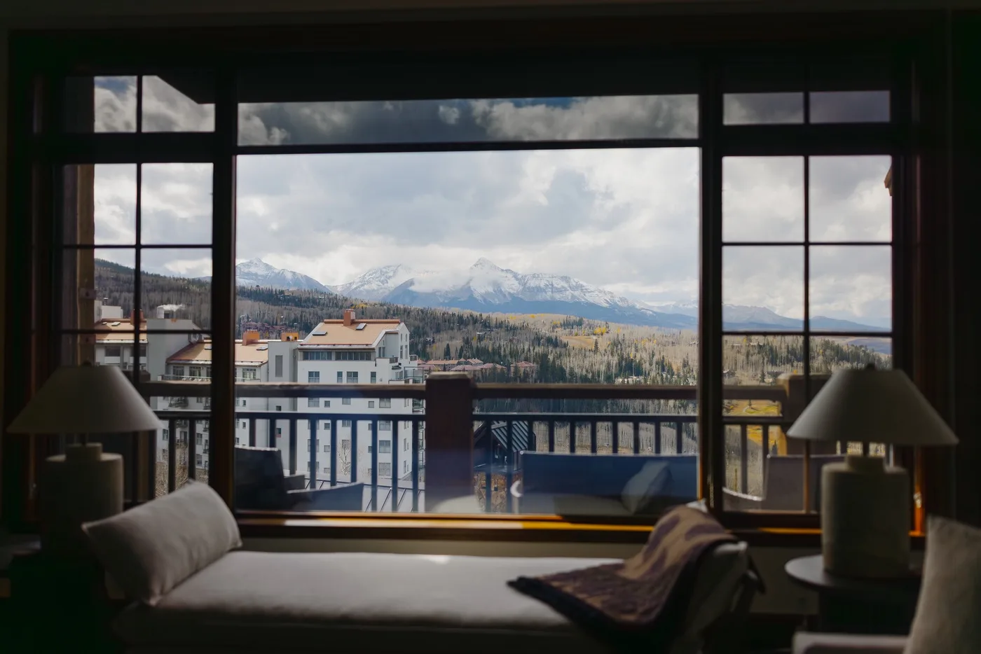 Una zona de descanso del dormitorio da a grandes ventanas con vistas a las montañas.