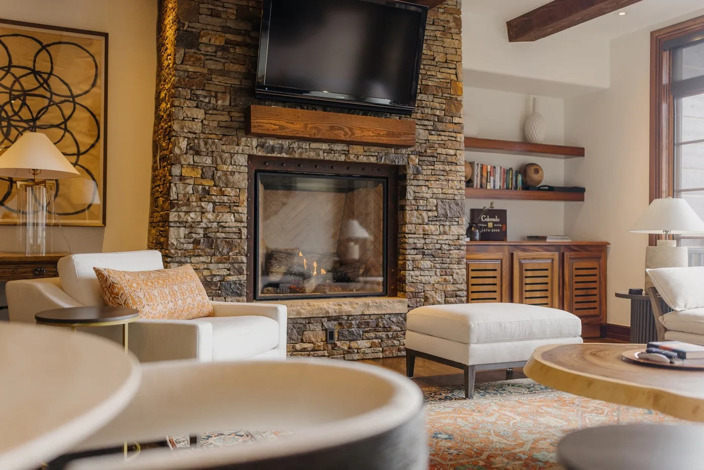 A living room with a stone fireplace, television, and seating.