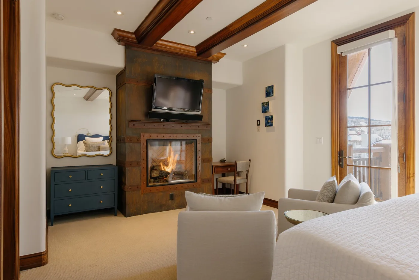 A bedroom sitting area with a fireplace, television, and seating.