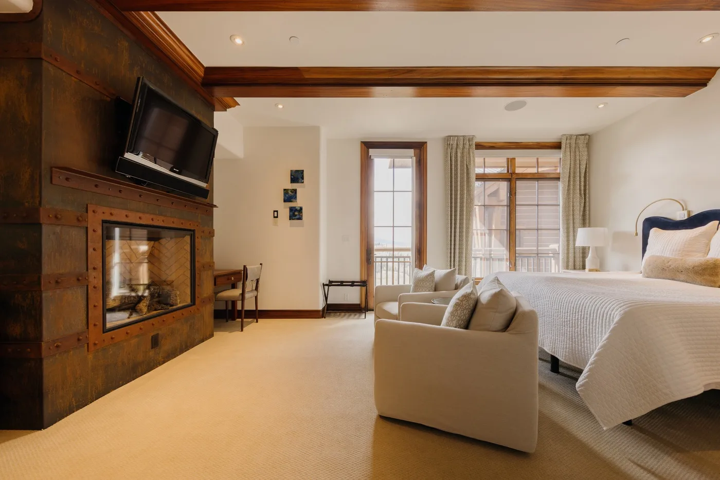 A bedroom with a bed, seating area, and fireplace along the wall.